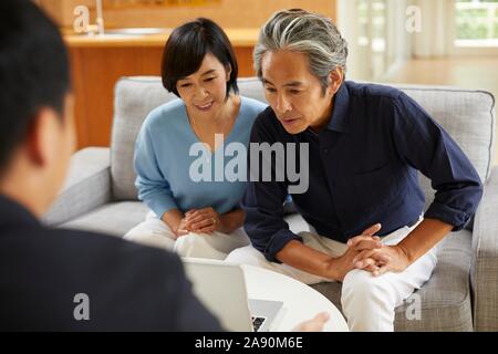 Senior Japanese couple at home with salesman Stock Photo