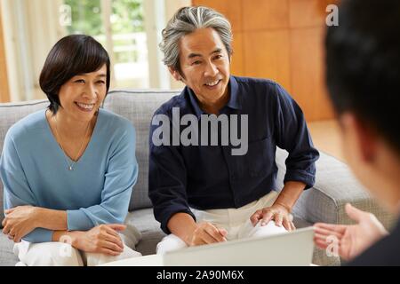 Senior Japanese couple at home with salesman Stock Photo