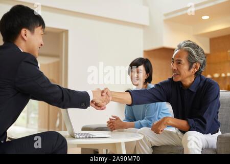 Senior Japanese couple at home with salesman Stock Photo