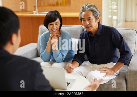 Senior Japanese couple at home with salesman Stock Photo