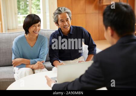 Senior Japanese couple at home with salesman Stock Photo