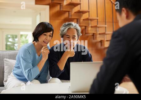 Senior Japanese couple at home with salesman Stock Photo