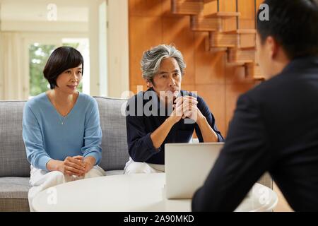 Senior Japanese couple at home with salesman Stock Photo