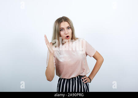 Gorgeous woman wearing shirt looking funny with popened mouth, keeping hand up Stock Photo