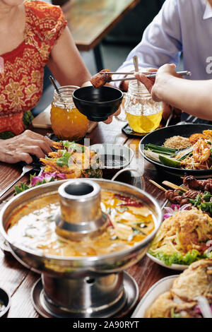 Group of people enjoying tasty dishes of Vietnamese cuisine during family dinner in restaurant Stock Photo