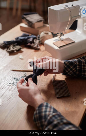 Tailor makes bow ties of woolen fabric. Work with sewing machine in a textile studio. Stock Photo