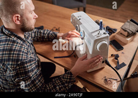 Tailor makes bow ties of woolen fabric. Work with sewing machine in a textile studio. Stock Photo