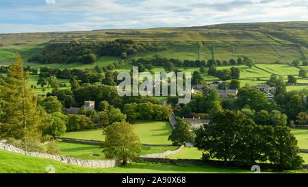 Summer evening sunlight on picturesque Dales village (church & houses) nestling in valley under upland hills - Arncliffe, North Yorkshire, England, UK