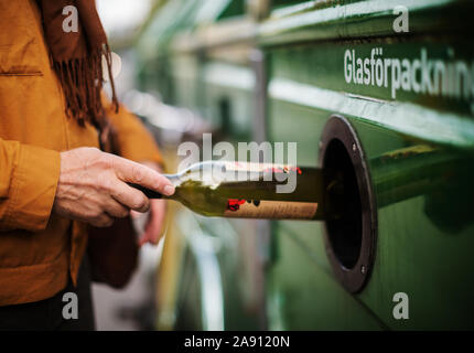 Hand putting bottle into recycling bin Stock Photo