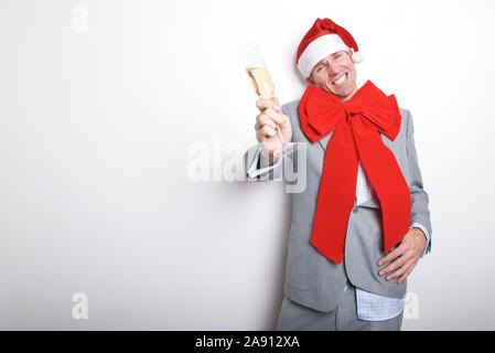 Drunk businessman dressed in Santa hat and big red bow for the holiday office party holding out a champagne toast with a cheesy grin Stock Photo