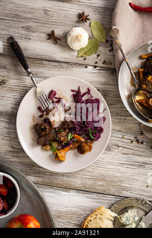 venison dish on old wooden table, with fruits jam, cheese and chestnuts, traditional winter dish with meat, hunting loot Stock Photo