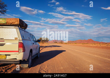 4x4 rental car equipped with a roof tent parks on a dirt road in Namibia Stock Photo