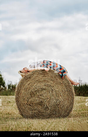Girl lying on bale of hay Stock Photo