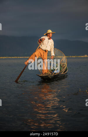 Burmese fisherman on a bamboo boat at sunrise