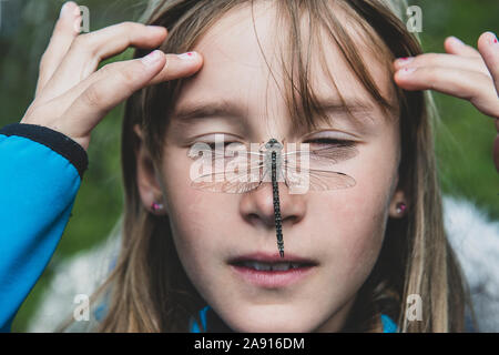 Dragonfly on girls face Stock Photo