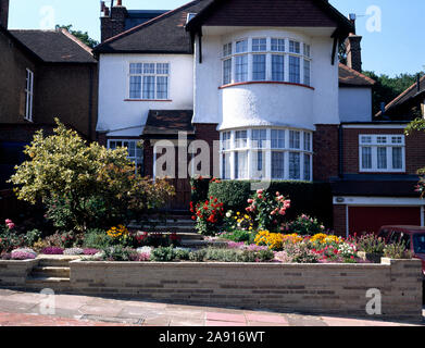 White  thirties villa with small terraced front garden., suburban style with low alpines and shrubs. Stock Photo