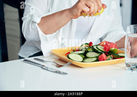 Hand squeezing lemon over salad Stock Photo