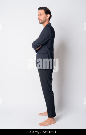 Full body shot profile view of handsome Hispanic businessman with arms crossed Stock Photo