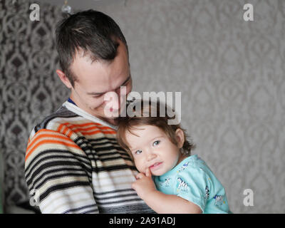 Loving father hugs the child in his arms. Baby 0-1 year old. Fatherly love. The relationship of father and son. A loving father holds a child in his Stock Photo