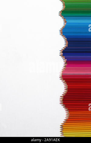 A vertical wavy line of colouring pencils in a rainbow order Stock Photo