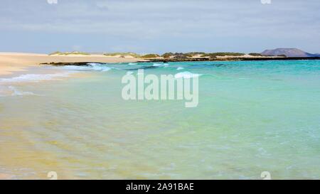 View of an empty Beach named Glass Beach with turquoise water and waves, near Corralejo town and natural dunes park on Fuerteventura island. Stock Photo