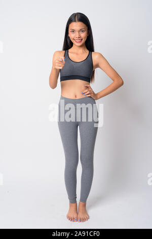 Full body shot of happy young Asian woman pointing at camera ready for gym Stock Photo