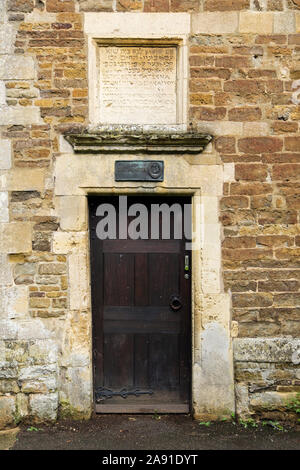 Sign and classical inscription above wooden door to old school building circa 1584 was restored in 1994. Oakham, Rutland, England, UK, Britain Stock Photo