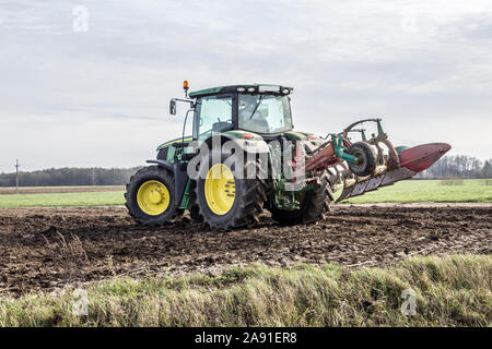 Wheel tractor with a raised plow, calls on the field. Plowing the land in late autumn. Podlasie, Poland. Stock Photo