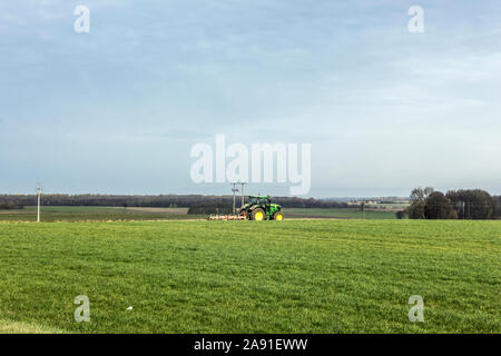 Wheel tractor with a multi-plow plow, plowing a green field. Plowing the land in late autumn. Podlasie, Poland. Stock Photo