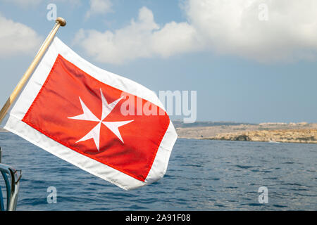 The merchant flag of Malta with white Maltese cross on a red background mounted on a stern of pleasure yacht Stock Photo