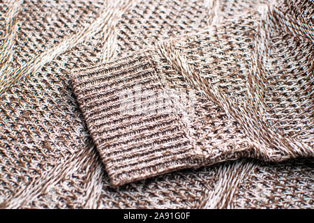 Knit texture of brown wool knitted fabric with cable pattern as background. Knitted brown sweater. Stock Photo