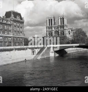 1950s, historical, View from Pont au Double across the river Seine to The Notre-Dame Cathedral, Paris, France. A medieval Catholic church on the IIe de la Cite in the 4th arrondissement of Paris, it is considered one of the finest examples of French Gothic architecture. Stock Photo