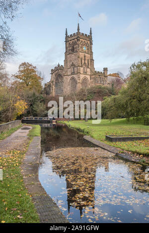Kidderminster, UK. 12th November, 2019. UK weather: after another chilly and wet start in Worcestershire, the autumn sunshine makes a welcome appearance. St. Mary's Church (the parish church of Kidderminster) stands majestically alongside a picturesque UK canal - its tower just visible through the fallen autumn leaves floating on the surface of the deep canal water. Credit: Lee Hudson Stock Photo