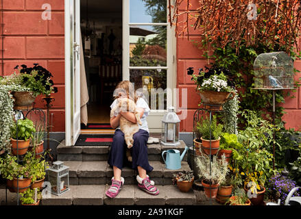 Girl sitting by her front door hugging a golden retriever dog Stock ...