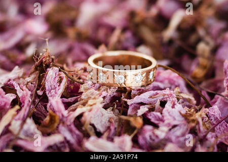 Wedding ring on dried rose petals Stock Photo