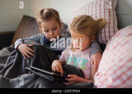 Sisters using digital tablet on sofa Stock Photo