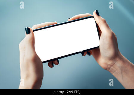 Close-up image of female holding smartphone horizontally with both hands at the office or corporate environment. Human resources, management, search o Stock Photo