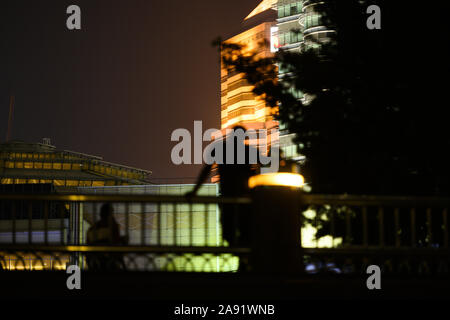 (Selective focus) Blurred silhouette of an unidentified man enjoying the view of the illuminated Kuala Lumpur city. Stock Photo