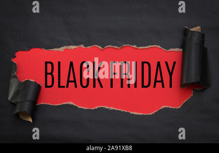 Black torn paper and text black friday on a red background Stock Photo