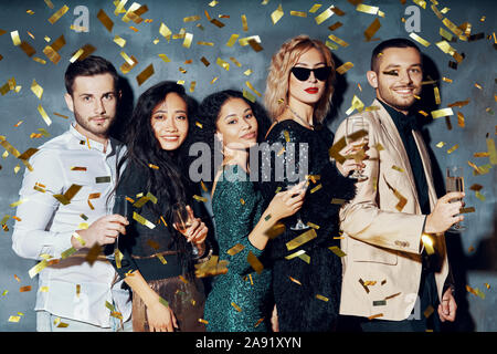 Happy young people dancing and having fun with confetti flying everywhere. Diverse group of people enjoy party. Holidays, celebration, nightlife and c Stock Photo