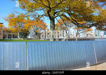 NEW YORK, NY - 04 NOV 2019: The American Immigrant Wall of Honor at Ellis Island, with colorful fall trees. colorful, Stock Photo