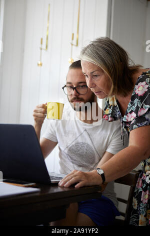 Senior woman using laptop with adult son Stock Photo