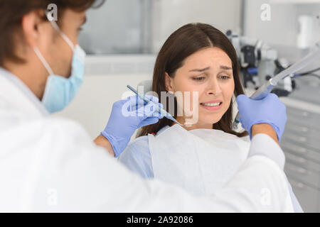 Frightened woman at dental office, looking panickly at dental tools Stock Photo