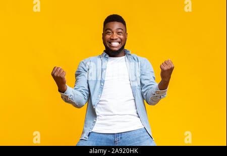Portrait of overjoyed black man celebrating success with clenched fists Stock Photo