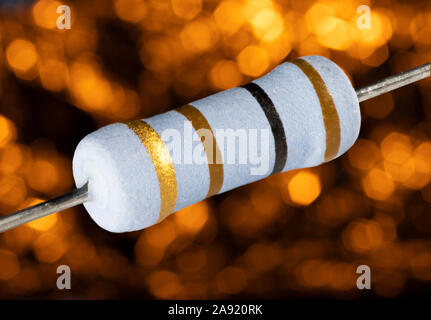 One hundred ohm rated resistor on a blurred orange background Stock Photo