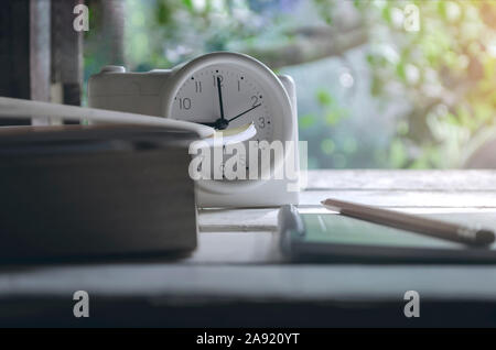 Class room in nature background with Green books, pencils, alarm clock, on a white wooden table with light orange Stock Photo