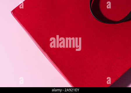 Red leather bag with black handle on the pink background. Free space for logo or advert. Package for shopping. Stock Photo
