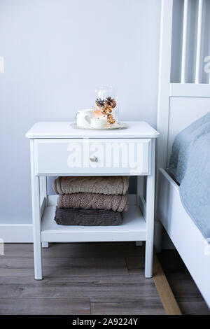 Christmas decor on the bedside table near the bed in the bedroom. Cozy interior details, soft and warm home decor. Stock Photo