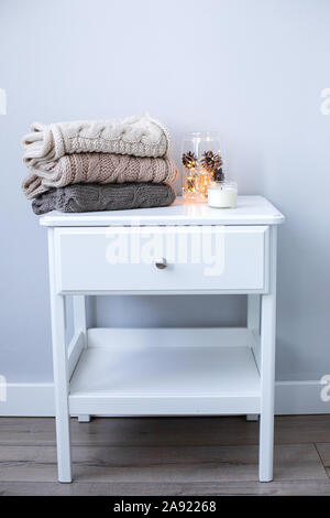 Christmas decor on the bedside table near the bed in the bedroom. Cozy interior details, soft and warm home decor. Stock Photo