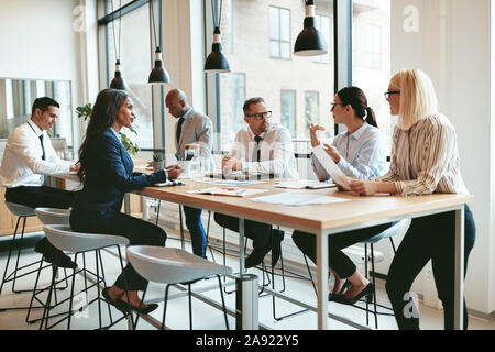 Focused group of diverse businesspeople discussing paperwork together during a meeting around a table in a modern office Stock Photo